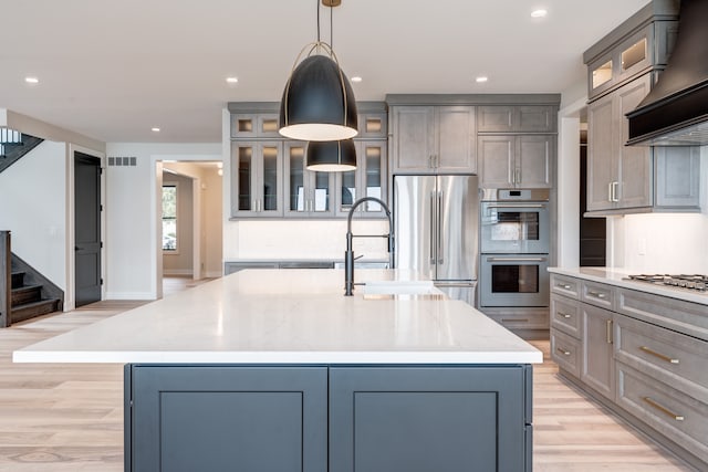 kitchen with a large island, stainless steel appliances, decorative light fixtures, and custom exhaust hood