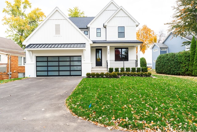 modern inspired farmhouse featuring a garage, covered porch, and a front lawn