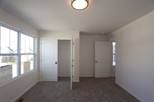 unfurnished bedroom featuring dark carpet and multiple windows