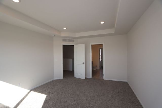 unfurnished bedroom with carpet flooring and a tray ceiling