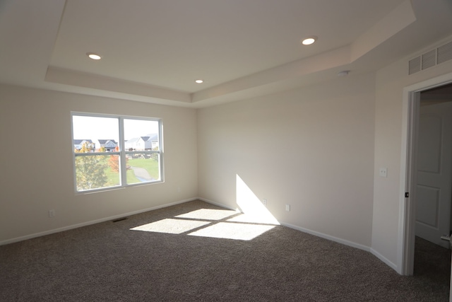 carpeted empty room featuring a tray ceiling