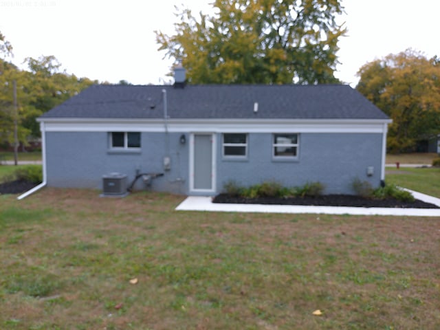 back of house featuring central AC unit and a lawn