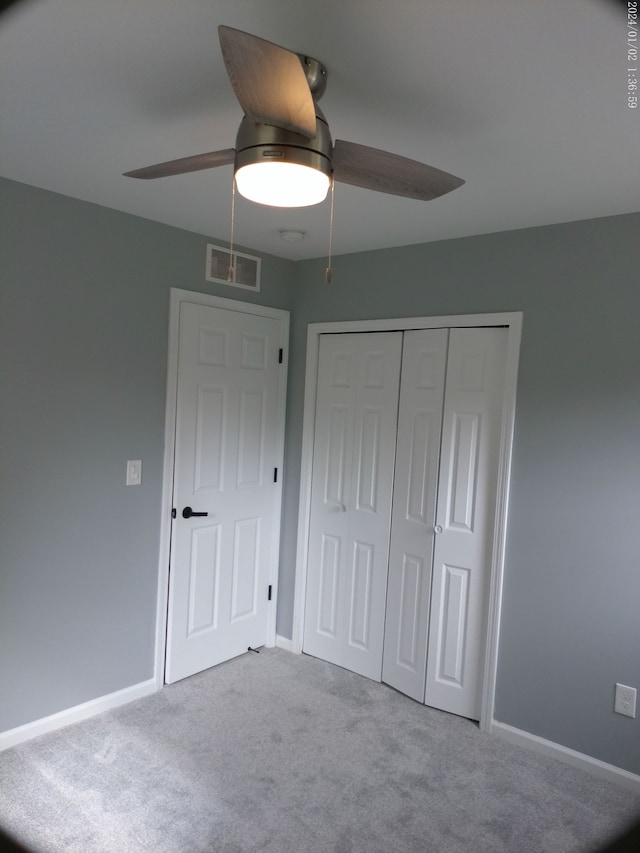 unfurnished bedroom with ceiling fan, light colored carpet, and a closet