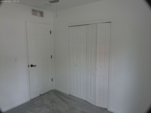 unfurnished bedroom featuring light colored carpet and a closet