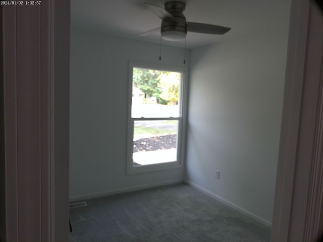 unfurnished room featuring ceiling fan and dark colored carpet