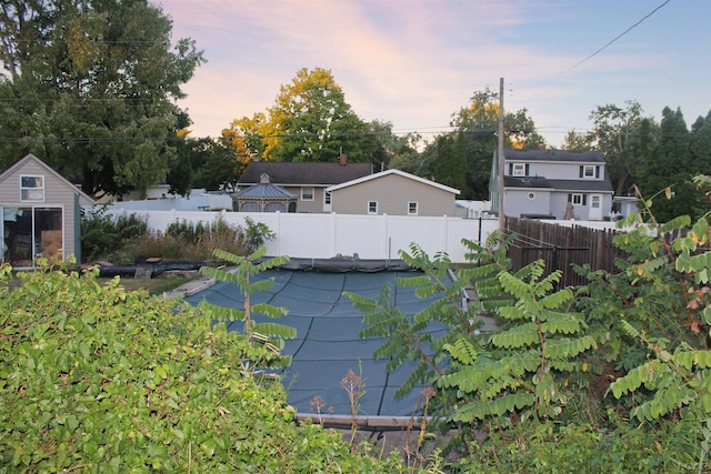 yard at dusk featuring a covered pool