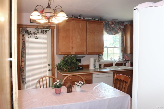 kitchen featuring sink, white dishwasher, a chandelier, and decorative light fixtures