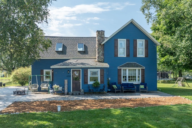 view of front of property featuring an outdoor living space with a fire pit, a patio area, a trampoline, and a front lawn