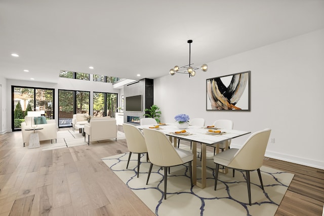 dining space with a tiled fireplace, light hardwood / wood-style flooring, and a notable chandelier