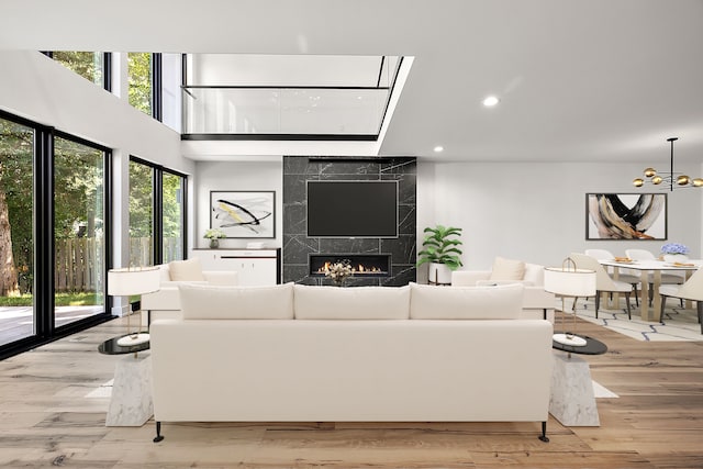 living room featuring a chandelier, light wood-type flooring, a fireplace, and a healthy amount of sunlight