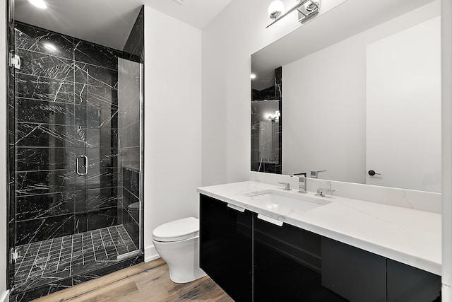 full bath featuring a marble finish shower, vanity, wood finished floors, and toilet