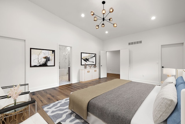 bedroom featuring ensuite bath, dark hardwood / wood-style flooring, high vaulted ceiling, and a notable chandelier