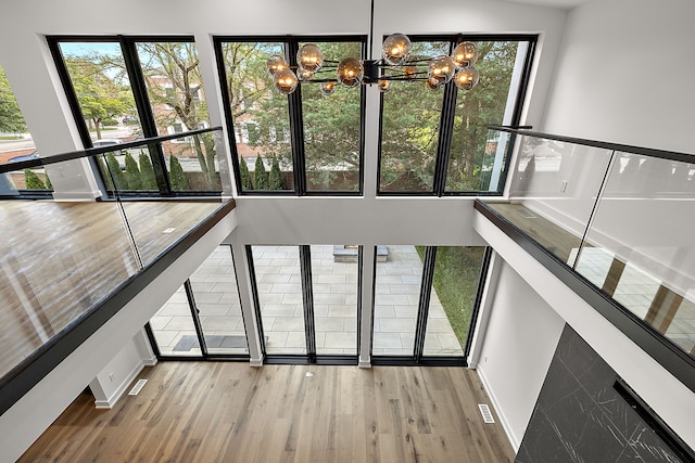 stairs featuring an inviting chandelier, a wealth of natural light, and wood finished floors