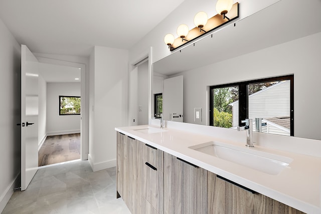 bathroom with double vanity, baseboards, and a sink