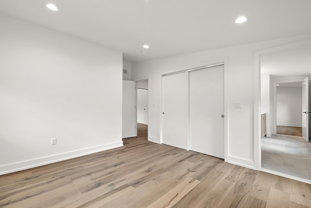 unfurnished bedroom featuring a closet, light wood-type flooring, and recessed lighting