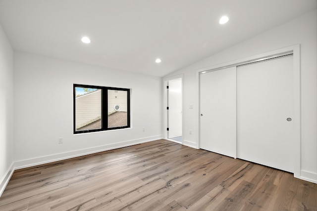 unfurnished bedroom featuring lofted ceiling, a closet, recessed lighting, and light wood-style floors