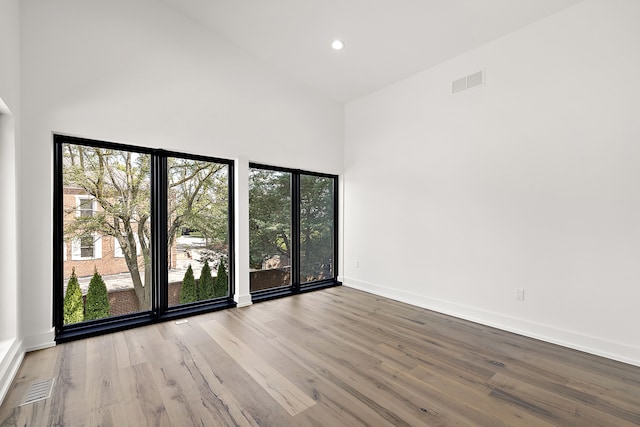 spare room with high vaulted ceiling and light hardwood / wood-style floors