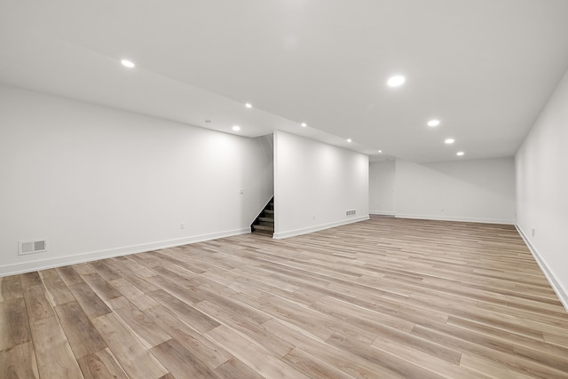 finished below grade area featuring light wood-style floors, stairway, visible vents, and recessed lighting