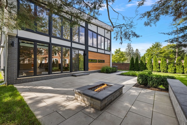 rear view of property featuring an outdoor fire pit and a patio area