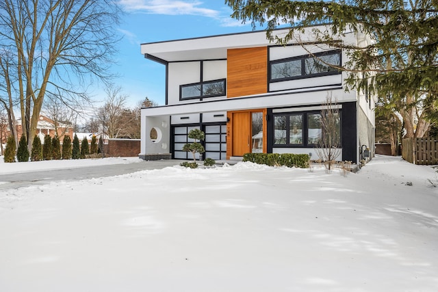 view of front of home featuring fence, an attached garage, and stucco siding