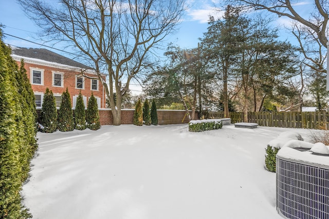 snowy yard featuring central air condition unit and fence