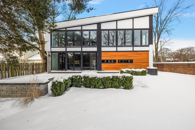 snow covered back of property with a garage and fence