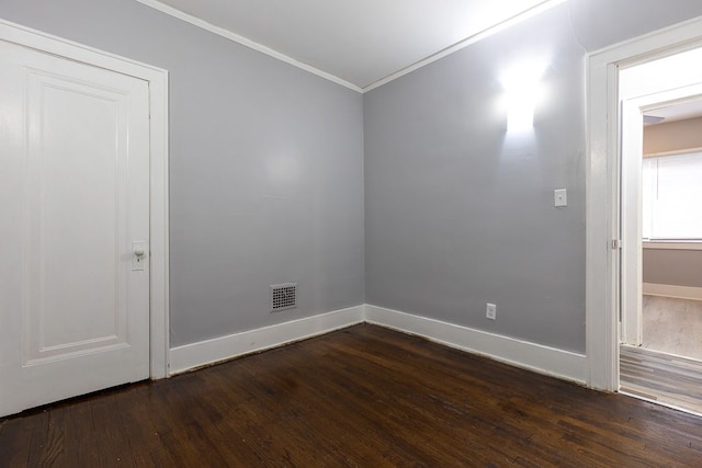 spare room with crown molding and dark wood-type flooring