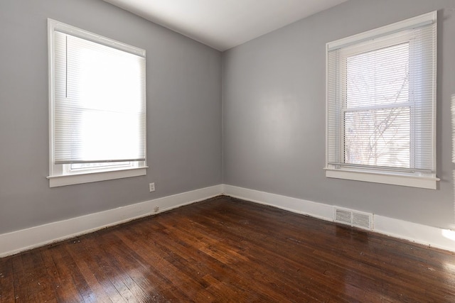 empty room featuring a healthy amount of sunlight and dark hardwood / wood-style flooring