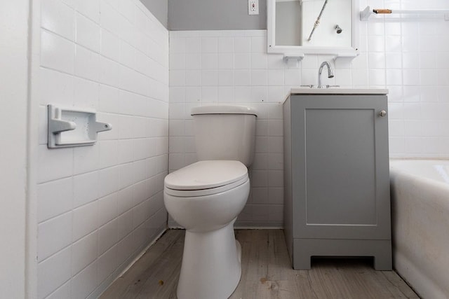 bathroom with hardwood / wood-style floors, vanity, and tile walls