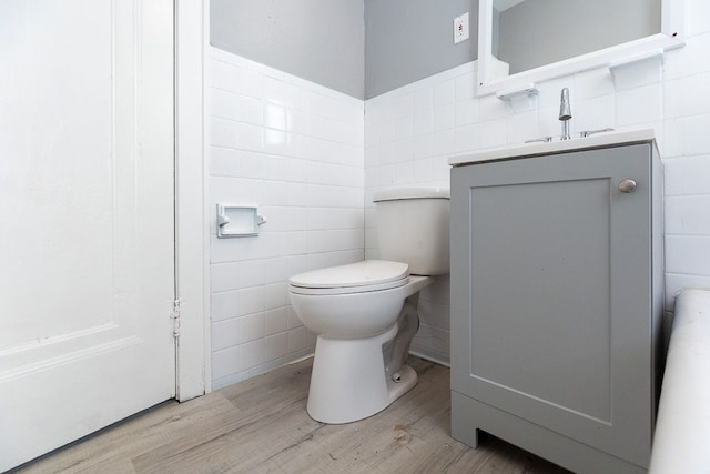 bathroom with vanity, toilet, wood-type flooring, and tile walls