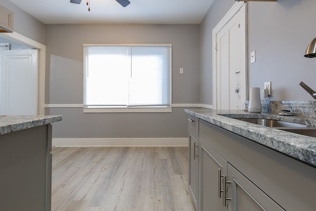 kitchen featuring light hardwood / wood-style floors, ceiling fan, gray cabinetry, and sink