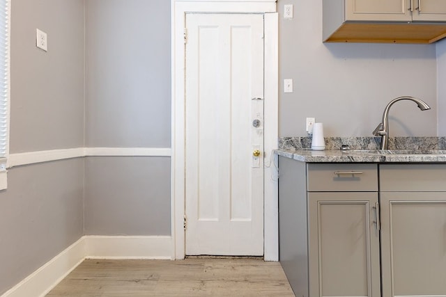 interior space with light wood-type flooring, gray cabinets, and sink