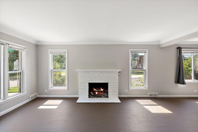 unfurnished living room featuring a wealth of natural light, dark hardwood / wood-style flooring, and a brick fireplace