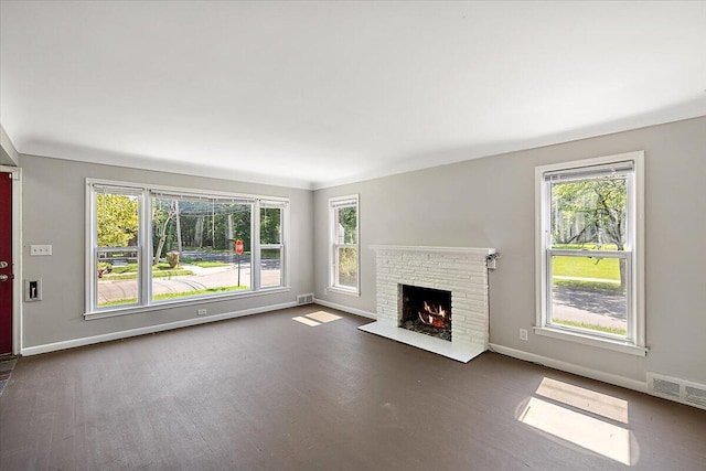 unfurnished living room featuring a fireplace, dark hardwood / wood-style flooring, and a healthy amount of sunlight