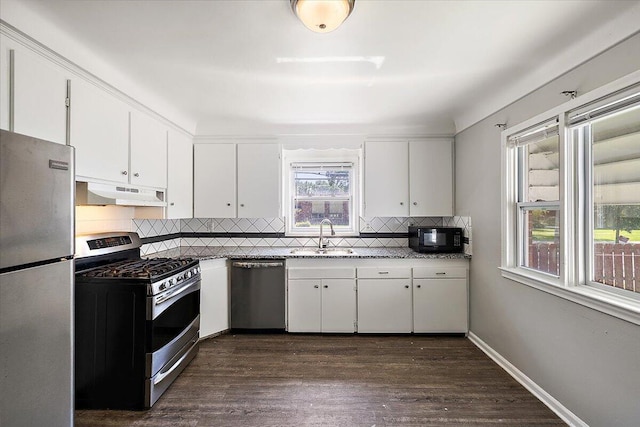 kitchen with backsplash, dark wood-type flooring, white cabinets, sink, and appliances with stainless steel finishes