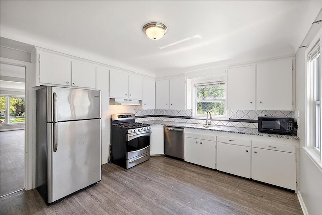 kitchen featuring backsplash, white cabinets, sink, light hardwood / wood-style flooring, and appliances with stainless steel finishes