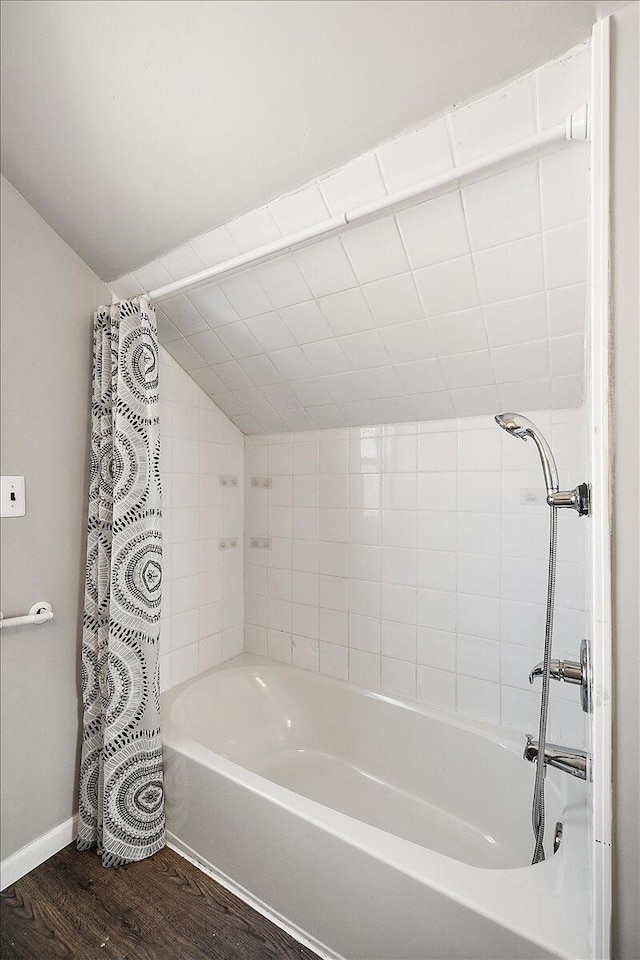 bathroom featuring shower / bathtub combination with curtain, wood-type flooring, and lofted ceiling