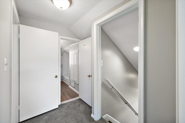 corridor featuring dark carpet and vaulted ceiling