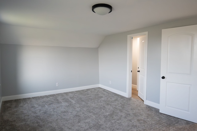 additional living space featuring dark carpet and lofted ceiling