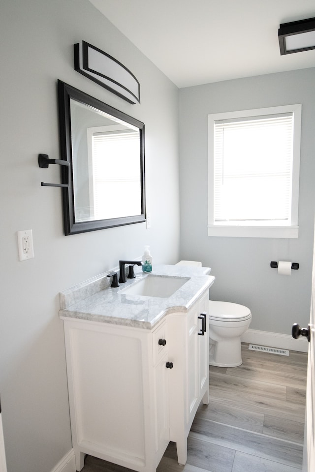 bathroom with toilet, vanity, and hardwood / wood-style flooring