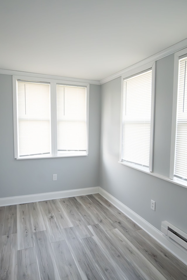 unfurnished room with crown molding, a baseboard radiator, and light hardwood / wood-style floors