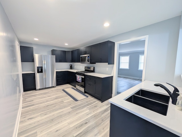 kitchen with appliances with stainless steel finishes, light hardwood / wood-style floors, and sink