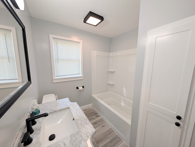 bathroom with washtub / shower combination, wood-type flooring, and sink