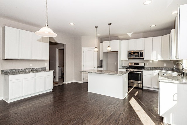 kitchen with a center island, sink, hanging light fixtures, white cabinetry, and stainless steel appliances