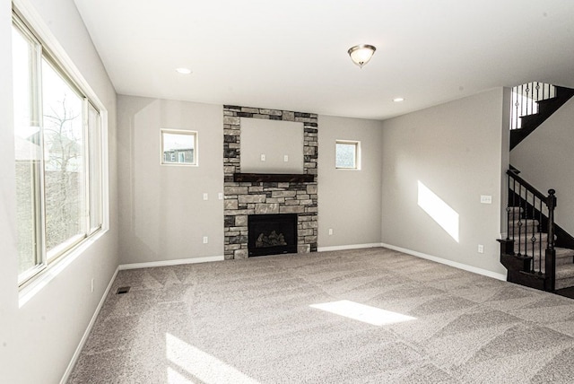 unfurnished living room with carpet, a fireplace, and a wealth of natural light