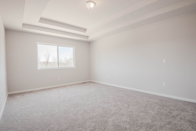 carpeted empty room featuring a raised ceiling