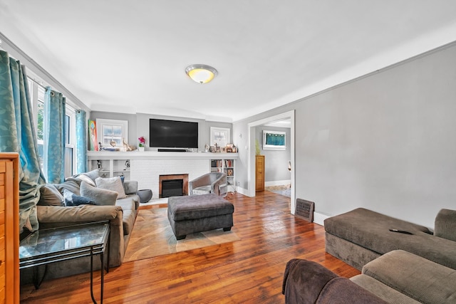 living room with a brick fireplace and hardwood / wood-style flooring