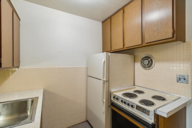 kitchen featuring white electric range oven, sink, and tile walls