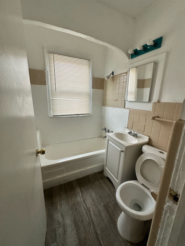 bathroom featuring toilet, vanity, wood finished floors, and tile walls