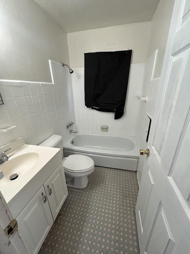 928 Mann Ave, Flint, MI 48503 - bathroom featuring tile walls, toilet, vanity, shower / tub combination, and wainscoting